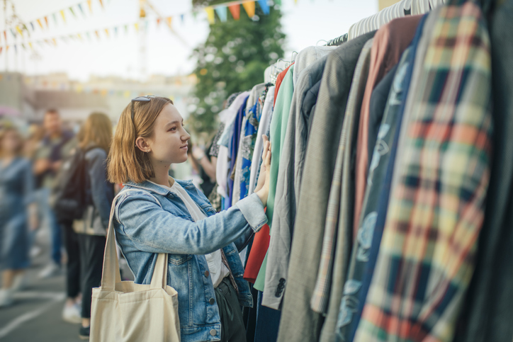 Young girl choosing clothes in a second hand market