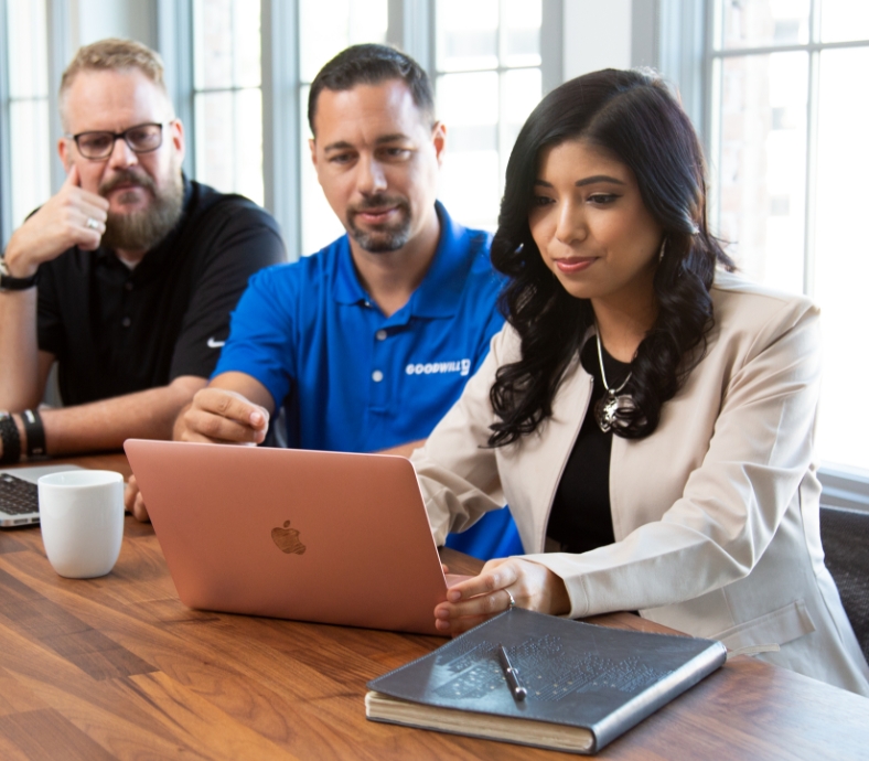 Three people sitting down looking at a computer