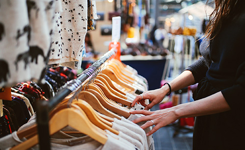 Someone looking through clothes on hangers on the rack