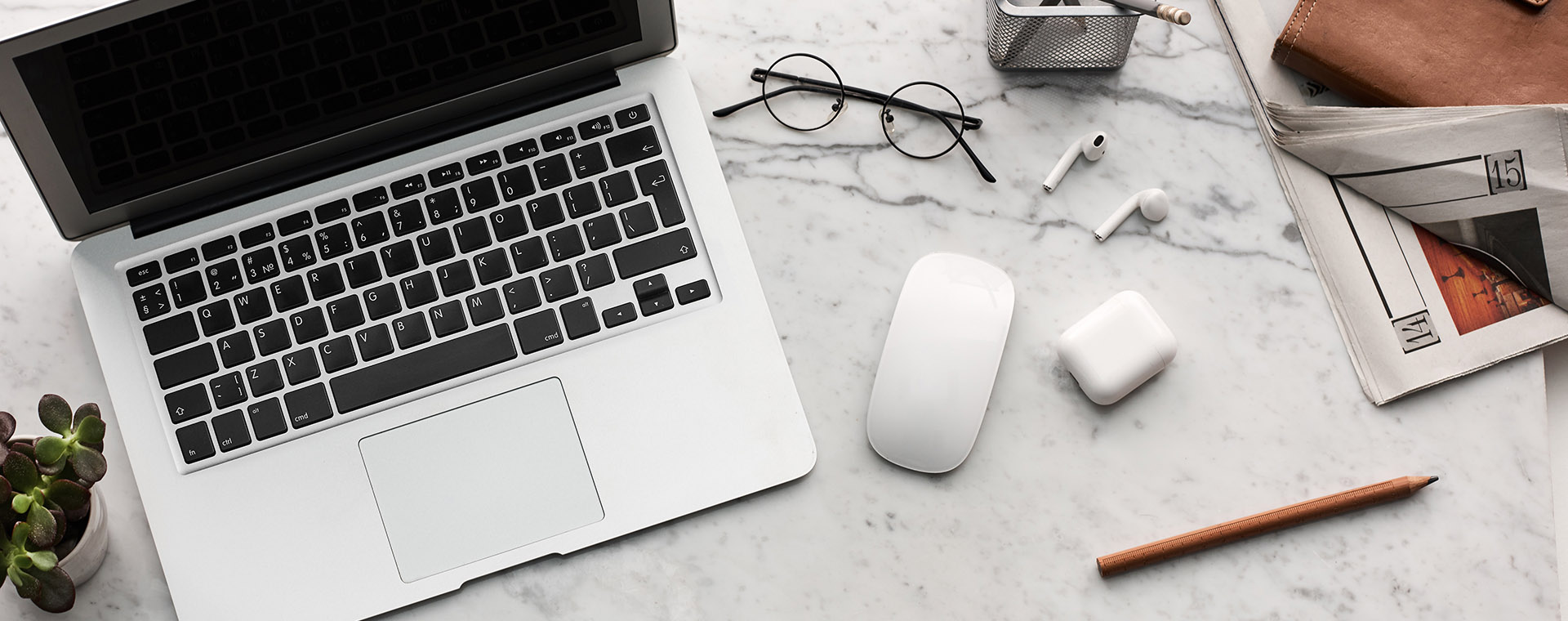 A laptop, mouse, and headphones scattered on a desk