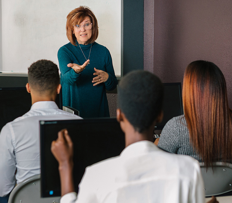 Women standing in front of a group of people teaching