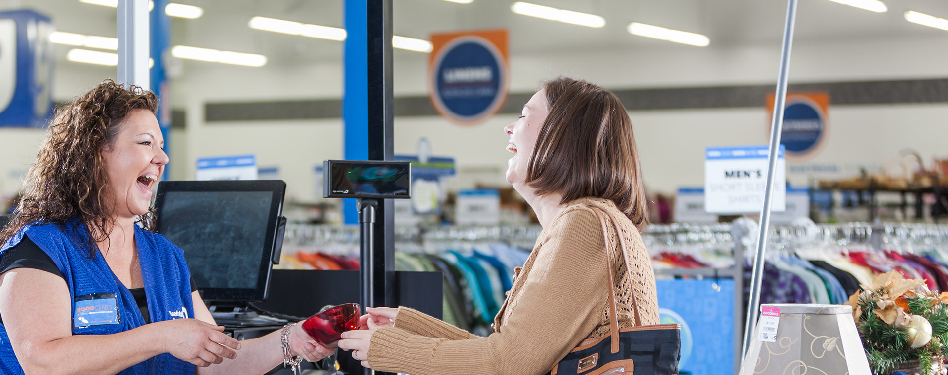 Women and employee smiling at a cash register