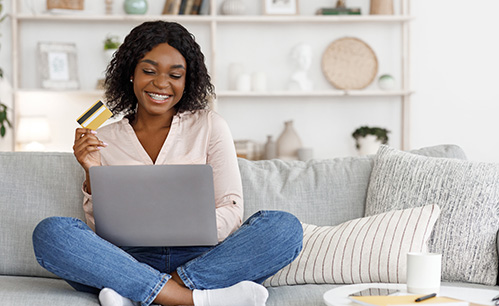 women sitting on the couch with her computer and credit card in hand