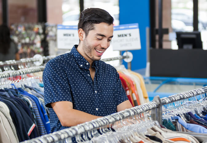man smiling while looking through clothing rack