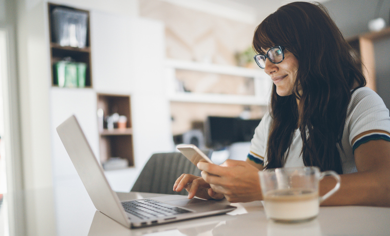 Young woman enjoying home office using laptop and smartphone