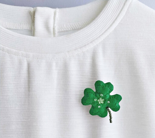 Handmade clover leaf brooch on white T-shirt. Celebrating Saint Patrick's Day Concept