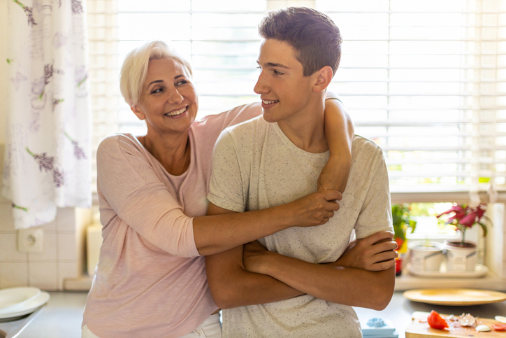 Mother hugging her teenage son in the kitchen | Goodwill industries of monocacy valley