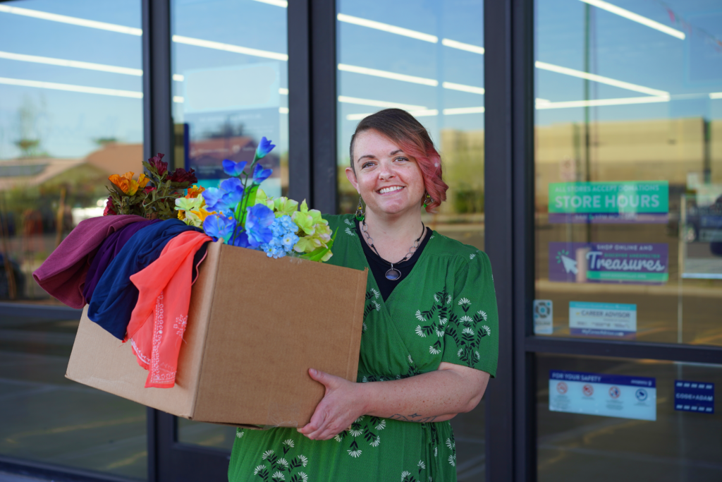 Woman holding a box of donations in front of a Goodwill store