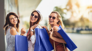 Three women holding shopping bags and smiling
