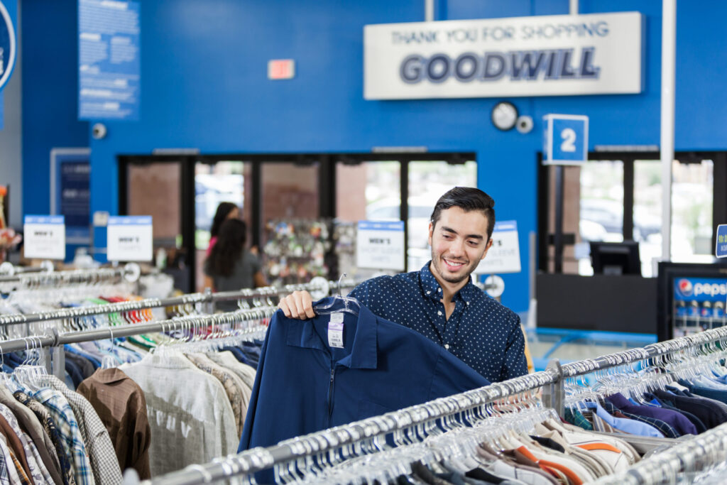 A man in a Goodwill store going through aisles of clothing