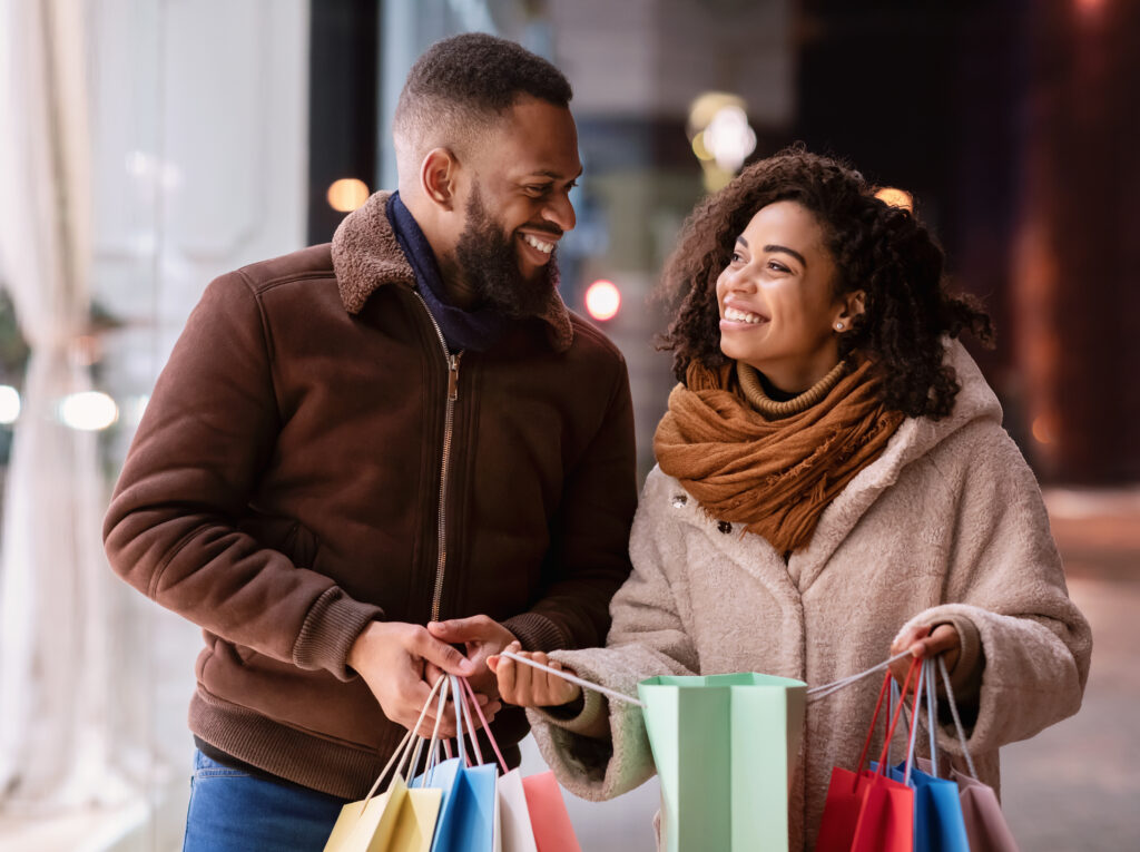 A man and a women walking outside holding shopping bags