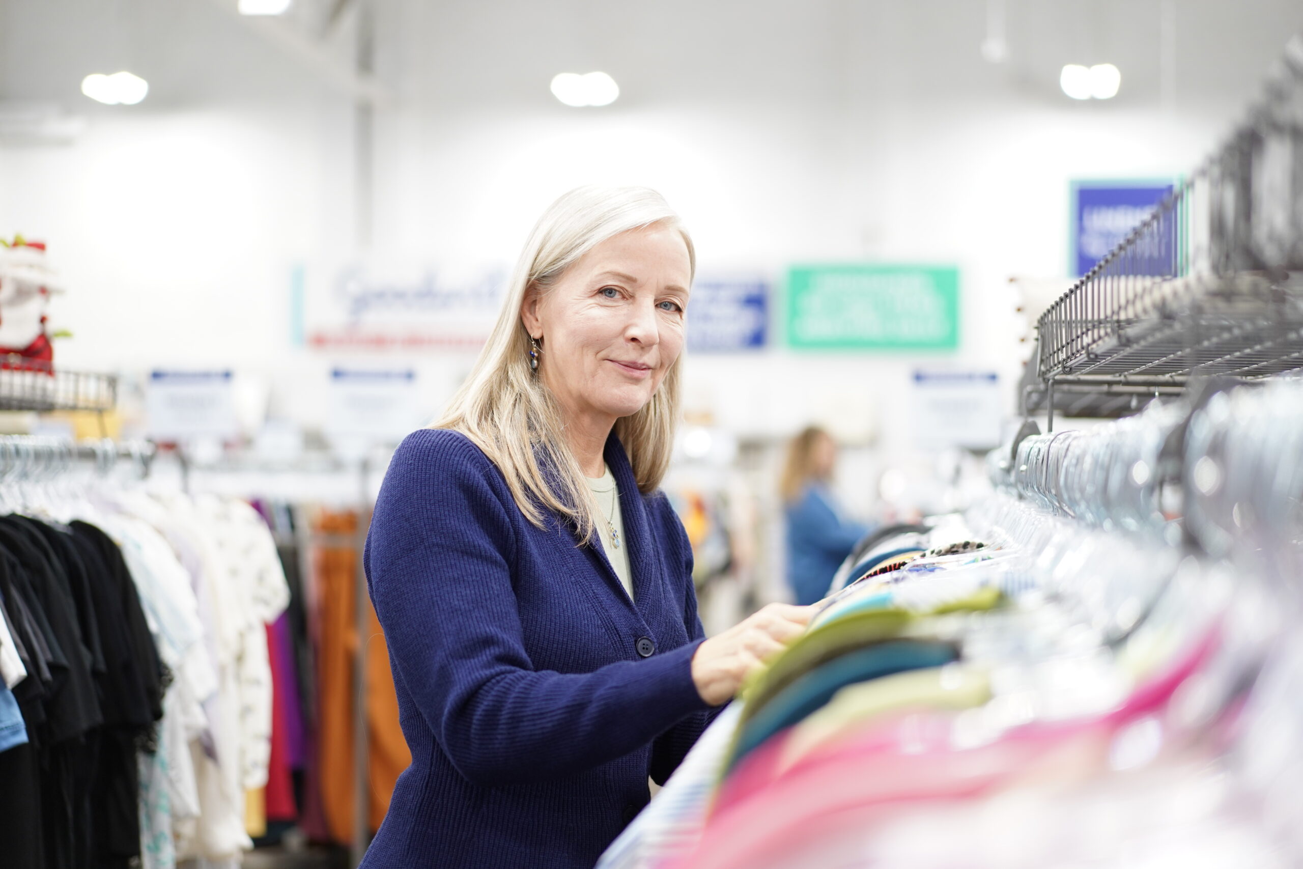 woman smiling, browsing clothing rack in thrift store
