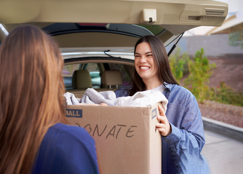 Image of a woman handing a box of donations to a Goodwill Donation Attendant